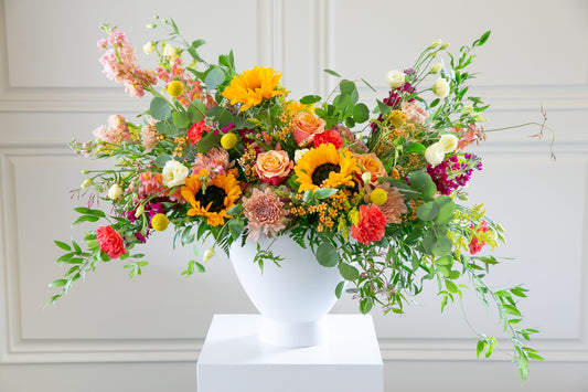 A large white urn with a multi-colored floral arrangement of fresh flowers