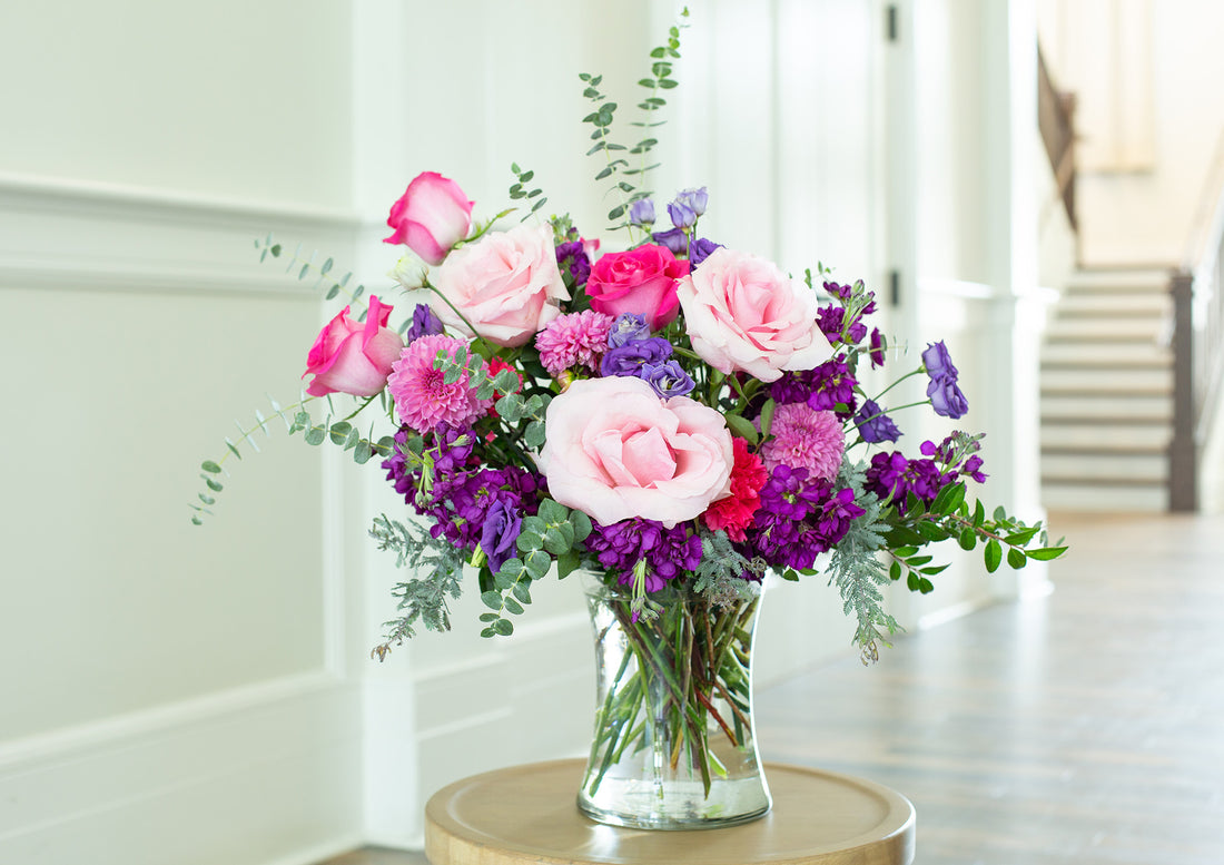A pink and purple flower bouquet in a clear glass vase