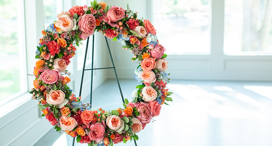 A large pink and orange flower wreath on an easel