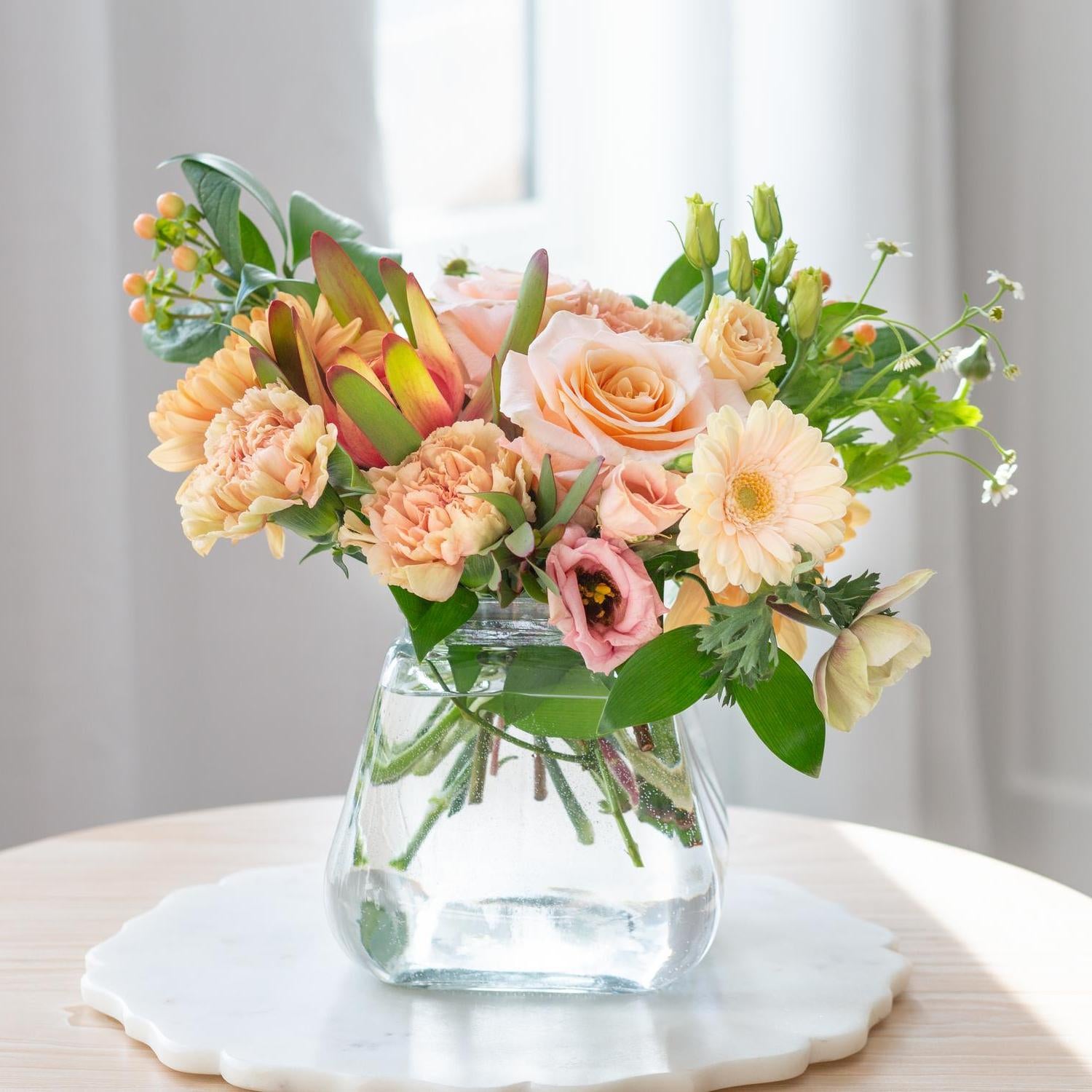 Small Rosie Posie square glass vase showcasing a mix of blush pink and coral flowers, including roses and hydrangeas, on a white surface with soft lighting.