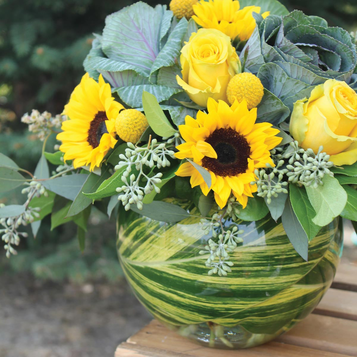 small bubble ball used as a vase with sunflowers yellow roses and ornamental cabbage