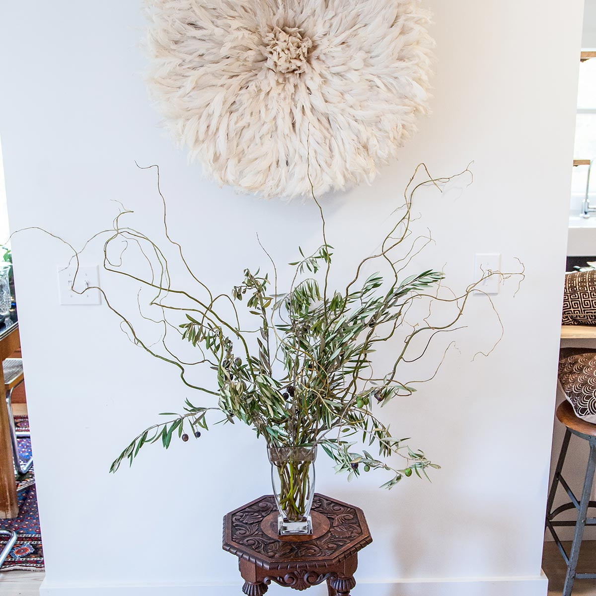large regal vase filled with olive branches and curly willow on end table
