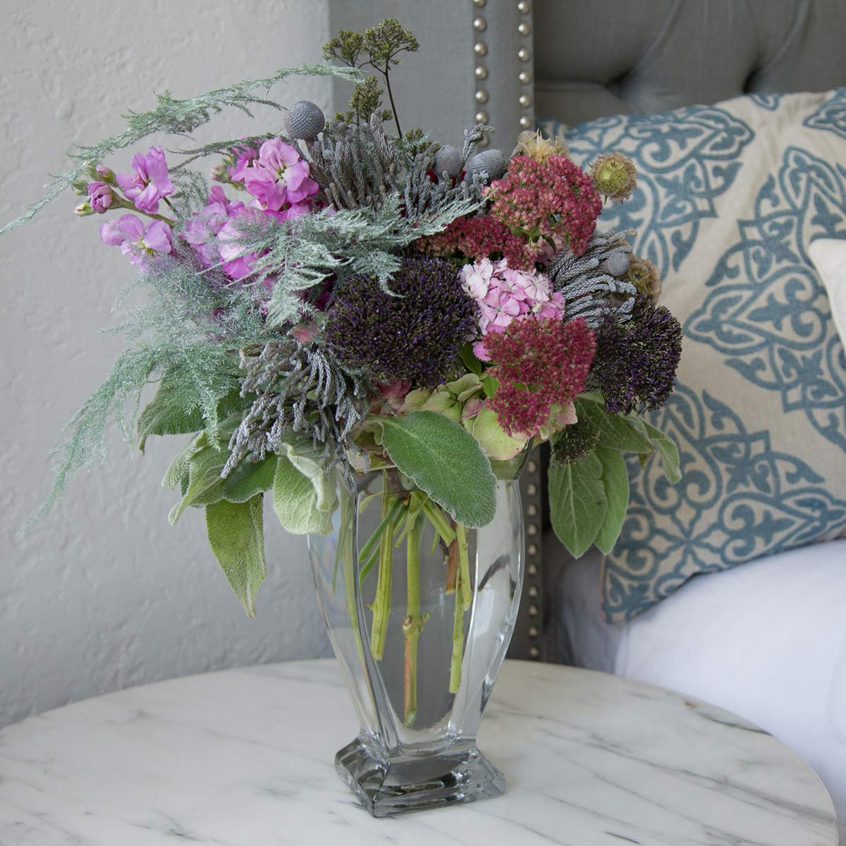 small regal vase filled with flowers on a nightstand